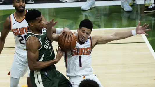 Giannis Antetokounmpo and Devin Booker battle for a loose ball during the second half of Game 3 of basketball's NBA Finals in Milwaukee, Sunday, July 11, 2021. Bucks won 120-100.