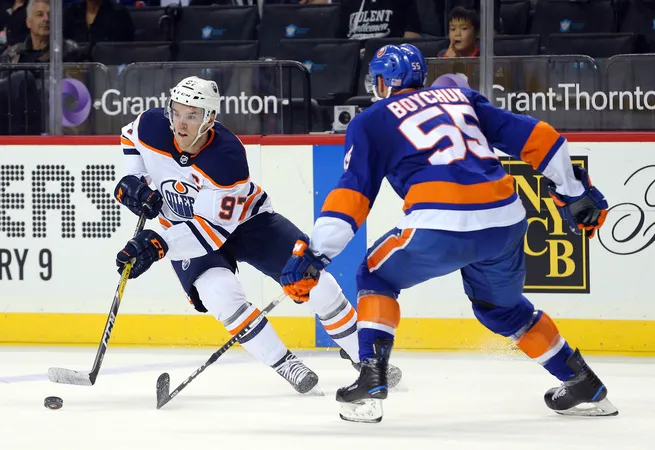 Connor McDavid plays the puck against Johnny Boychuk of the New York Islanders