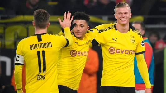 Dortmund's Norwegian forward Erling Braut Haaland (R) celebrate scoring the 4-1 goal with his teammates Dortmund's German forward Marco Reus (L) and Dortmund's English midfielder Jadon Sancho (C) during the German first division Bundesliga football match